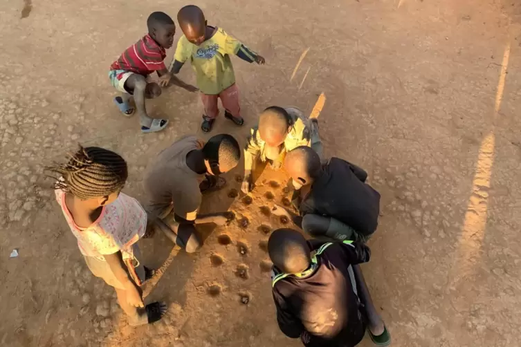 Kinder in Tabacongo, in der Demokratischen Republik Congo, beim Kisolo, das bei uns mit einem Brett gespielt wird und Steinchens
