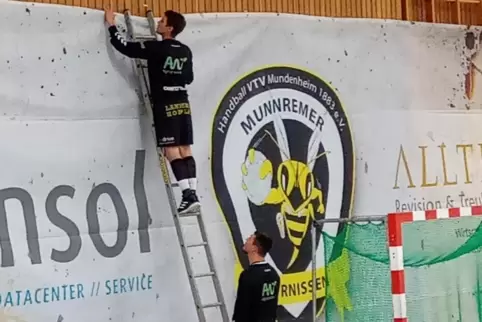 Auf dem Weg nach oben: Marco Binnes richtet das Werbebanner, Thoren Pönisch sichert die Leiter.