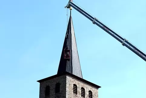 Recht spektakulär mit Hängekorb am Mobilkranausleger werden die Arbeiten am Kirchturm in Leimen ausgeführt. 
