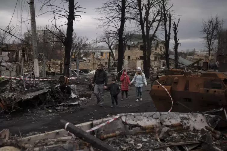 Eine Familie geht in Butscha, einem Kiewer Vorort, an zerstörten russischen Panzern vorbei. Inzwischen sind die Russen abgezogen