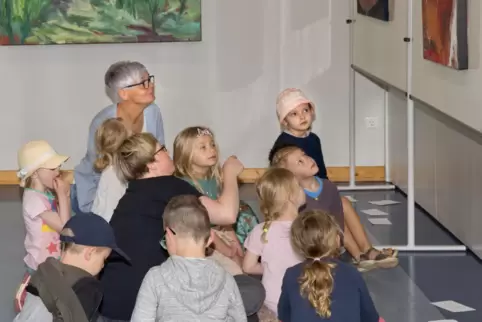 Die Kinder schauen sich die Bilder der Künstlerin Ruth Genné genau an – schließlich sollen sie bald eigene Kunstwerke anfertigen