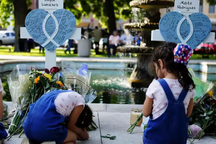 Kinder trauern um die Opfer des Massakers an einer Grundschule in Uvalde, sie knien vor Kreuzen mit Herzen, die im Gedenken an d