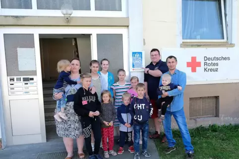 Die zwölfköpfige Familie T. aus Mariupol mit Jan Hendrik Prager vor dem neu angebrachten Schild von der UNO.