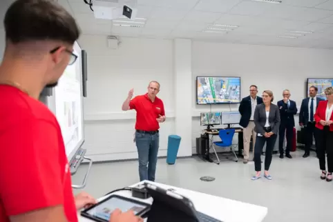Azubi Linus Adam und Ausbilder Sven Mahler demonstrieren Ministerin Hubig einen virtuellen Säulenbohrer.
