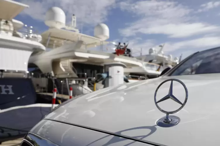 Ein teurer Mercedes-Benz vor einer Luxusjacht. 