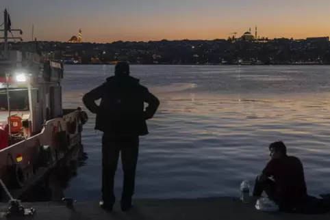 Istanbul bei Sonnenuntergang: Zwei Männer schauen auf das Goldene Horn, den Meeresarm am Bosporus.
