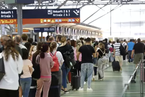  Passagiere stehen in einer Schlange von mehreren hundert Metern für die Sicherheitskontrolle am Flughafen Köln-Bonn an. 