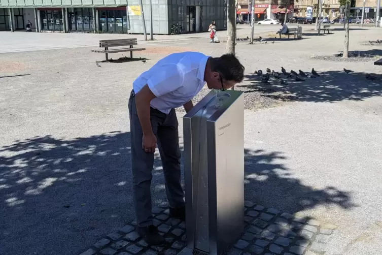 Bürgermeister Ralf Eisenhauer trinkt einen Schluck am neuen Trinkwasserspender.