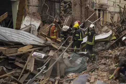 Krieg in der Ukraine: Feuerwehrleute entfernen Trümmer nach einem russischen Raketenangriff in Charkiw. Foto: Evgeniy Maloletka/