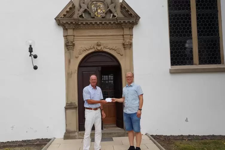 Klaus Hein (links) übergibt die Spendensumme an Pfarrer Sebastian Best. 