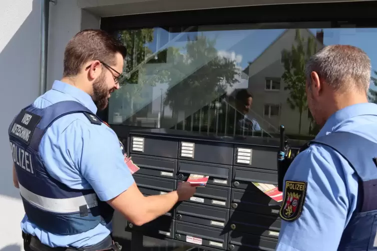 Hier werfen Polizeioberkommissar Petry und Polizeikommissar Van de Kerkhof (von links) Infomaterial in die Briefkästen eines Meh