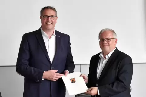 Digitalisierungsminister Alexander Schweitzer übergibt den Förderbescheid an Landrat Hans-Ulrich Ihlenfeld.