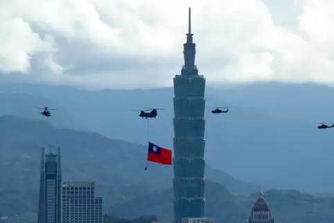 Militärhubschrauber fliegen am höchsten Wolkenkratzer in Taipeh mit einer riesigen Taiwan-Flagge vorbei.