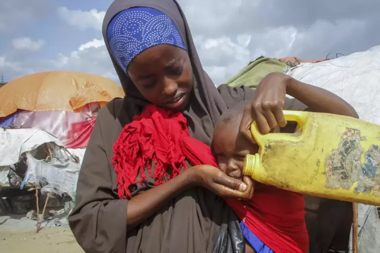 Eine somalische Frau, die aus den von der Dürre betroffenen Gebieten geflohen ist, gibt ihrem Kind Wasser aus einem Plastikbehäl