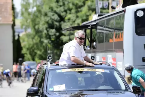 Bis auf einmal war er immer dabei: Rennleiter Albert Müller 2014 im „Chef-Auto“ vor dem heranrasenden Peloton (hinten links) bei