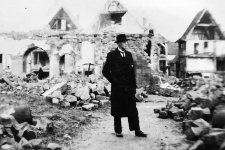 Stadtpfarrer Georg Biundo nach dem Bombenangriff am 29. Dezember 1944 in Annweiler zwischen kriegszerstörten Gebäuden. 