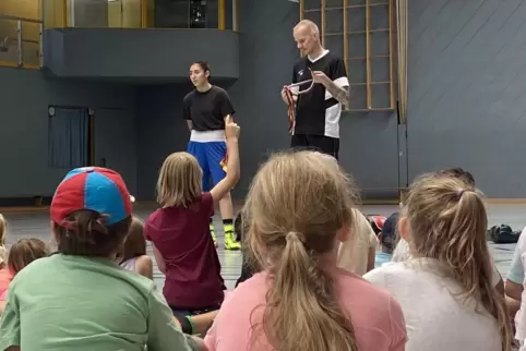 Beeindruckende Trophäensammlung: U19-Europameisterin Asya Ari und Trainer Andreas Riedel zeigen den Kindern in der Sporthalle Am