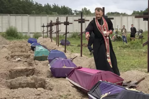  Ein Priester betet während einer Zeremonie für nicht identifizierte Zivilisten, die während der russischen Besatzung in Butscha