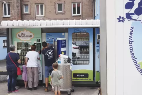 Während Michael Groß den milchautomaten von Bauer Brassel befüllt, kaufen sich Kunden Eis am benachbarten Automaten der Eiswerks