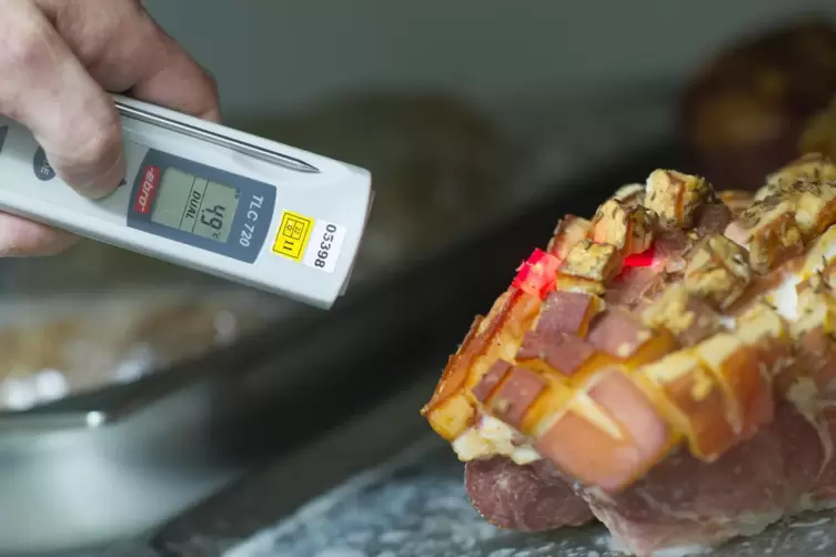 Hier überprüft ein Lebensmittelkontrolleur die Temperatur einer Fleischware.