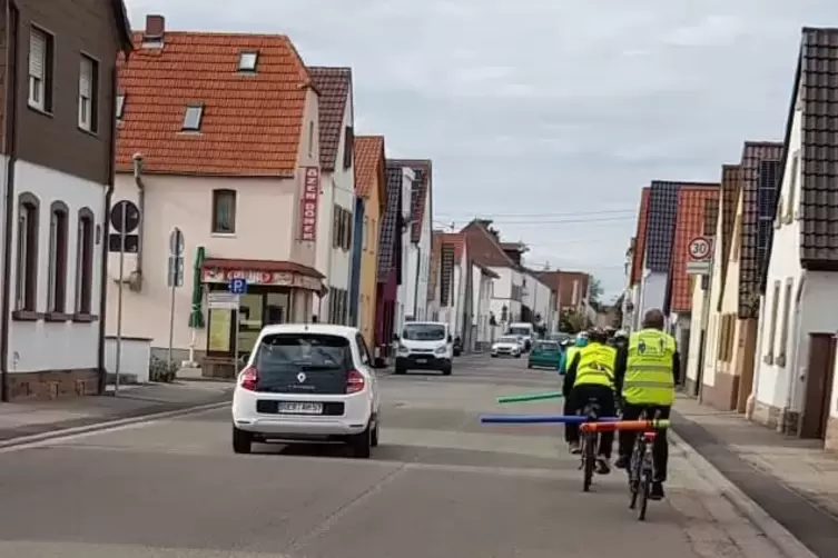 Auf der Germersheimer Straße: Radfahrer mit Schwimmnudeln auf dem Gepäckträger. 
