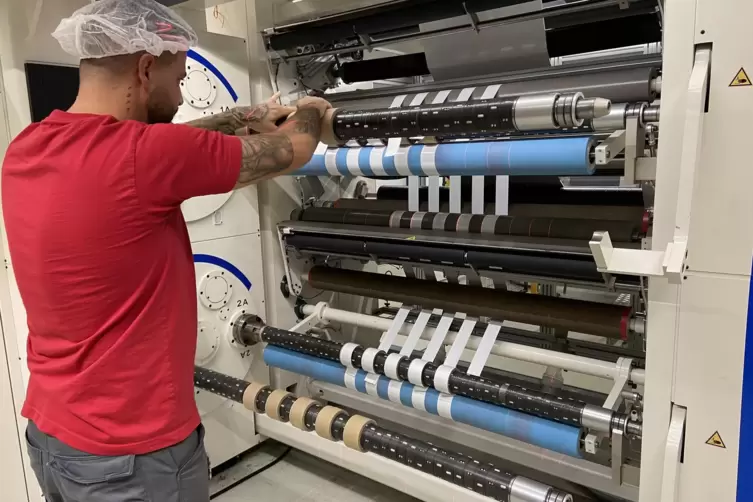 Die Schneidemaschine wird eingerichtet: Hier werden die bedruckten Folien auf Verpackungsbreite geschnitten und aufgewickelt.
