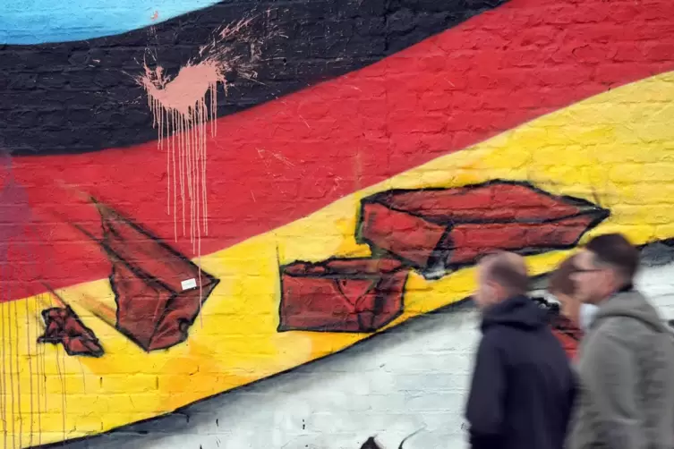Passanten in Berlin vor einem Wandgemälde.