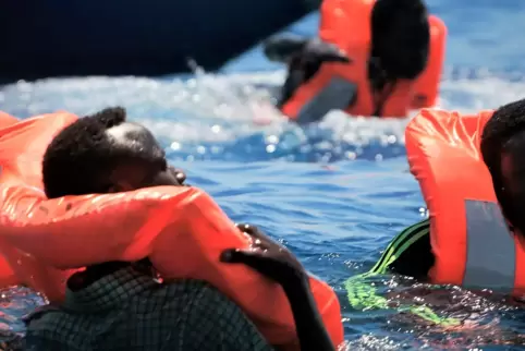Migranten schwimmen mit Rettungswesten im Mittelmeer. 