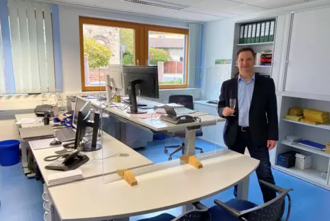 Mit einem Glas Sekt genießt VG-Bürgermeister Frank Rüttger die neuen Büros mit höhenverstellbaren Schreibtischen.