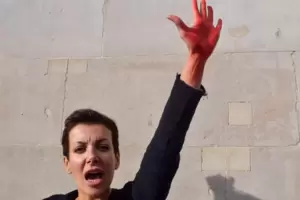 Eine Frau hebt eine mit Kunstblut beschmierte Hand auf dem Trafalgar Square in London, während die Proteste für Mahsa Amini und Eine Frau hebt eine mit Kunstblut beschmierte Hand auf dem Trafalgar Square in London, während die Proteste für Mahsa Amini und