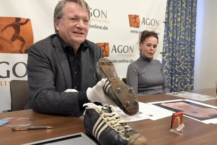 Auktionator Wolfgang Fuhr präsentiert die Schuhe, die Horst Eckel im WM-Finale 1954 trug. Sie sollen versteigert werden. Rechts 