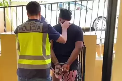 Ein Polizist führt auf Mallorca einen der mutmaßlichen 16 Liebesschwindler ab. 