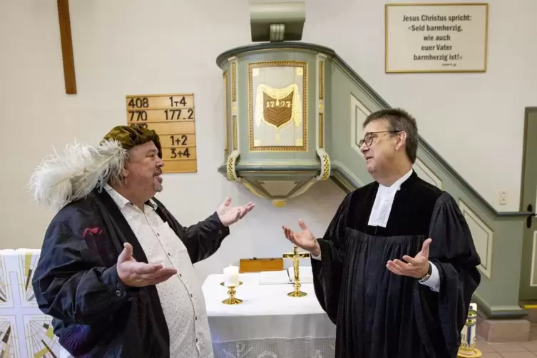 Der aktuelle Pfarrer Wolfgang Hust trifft auf einen „Vorgänger“, auf Pfarrer Kieffer (Axel Rung). Im Hintergrund ist die spätbar