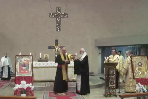 Bischof Karl-Heinz Wiesemann übergibt eine Reliquie als Geschenk. 