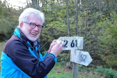 Wanderpate Willi Richter von den Naturfreunden hat ein Tüchlein dabei, mit dem er am Harzbornhaus zwei Wanderweg-Schilder putzt.