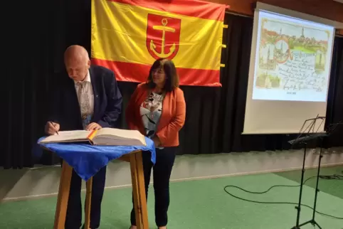 Ortsvorsteher Günther Henkel trägt sich ins Goldene Buch der Stadt Ludwigshafen ein, beobachtet von OB Jutta Steinruck. 