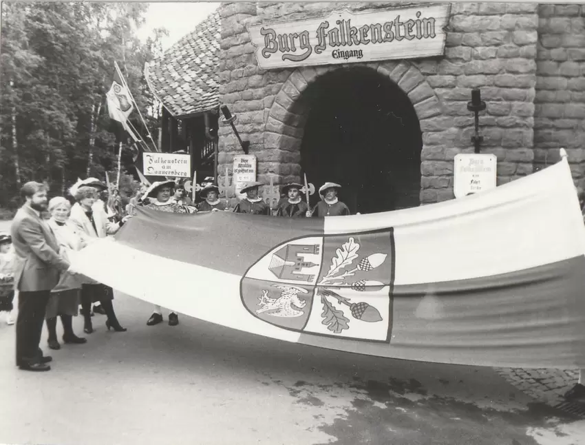 Die Falkensteiner Ortsflagge vorm Burgtor der Burg Falkenstein, links stehen Familie Schneider und Falkensteins OB Norbert Fisch