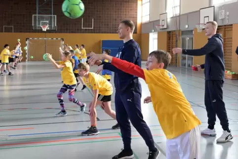 Stars und ganz normale Menschen: Die Rhein-Neckar-Löwen Kristjan Horzen (Bildmitte) und David Späth (rechts) trainieren Schüler 