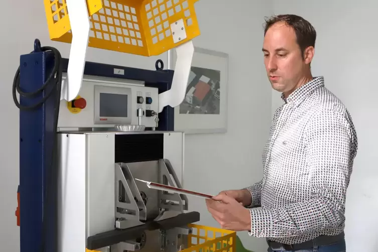 Sebastian Schmitt und ein Ausstellungsst&uuml;ck: die Rotationsstanzmaschine, die das Unternehmen weiterentwickelt. 