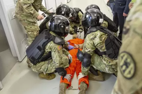 US-Militärangehörige demonstrieren, wie randalierende Insassen fixiert werden.