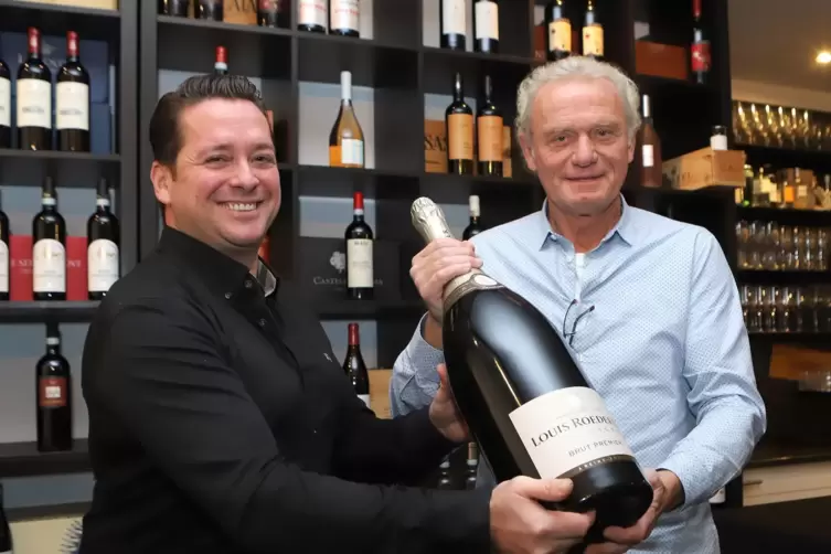 Adriano Casella (links) und Hans-Peter Briegel verkaufen Gläser einer Sechs-Liter-Champagner-Flasche für den guten Zweck.