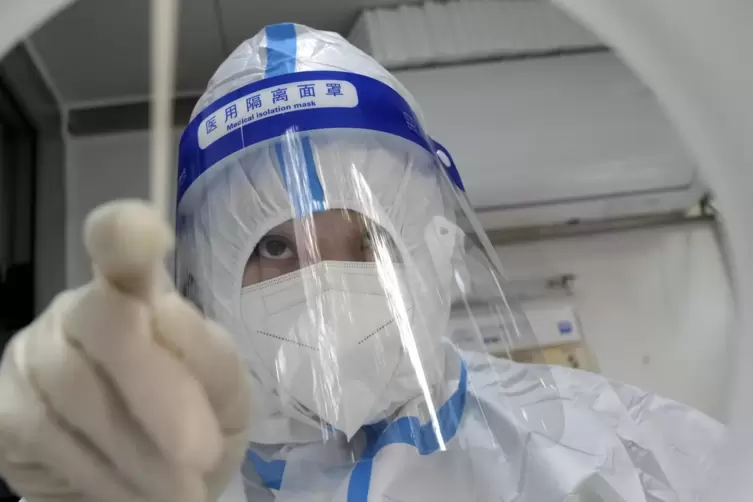 Nur noch selten: Ein Mitarbeiter in Schutzkleidung führt in Schanghai einen Coronatest durch. 