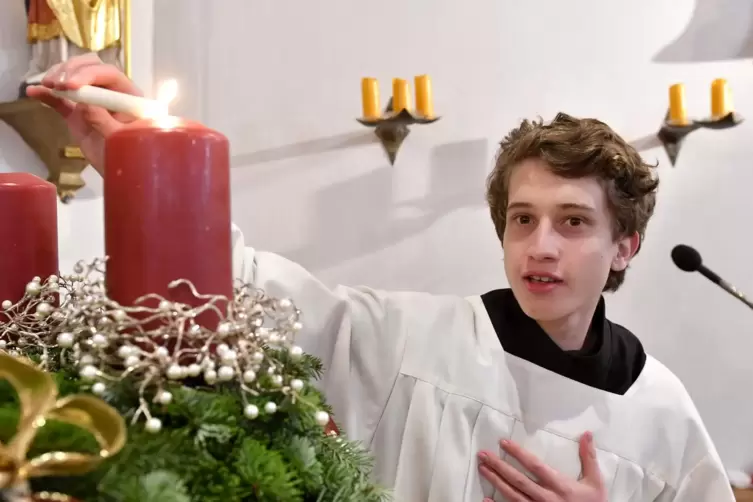Messdiener Julian zündet die Kerzen des Adventskranzes in der Edith-Stein-Kirche an.