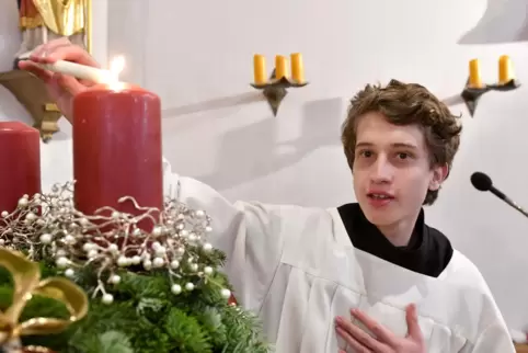 Messdiener Julian zündet die Kerzen des Adventskranzes in der Edith-Stein-Kirche an.