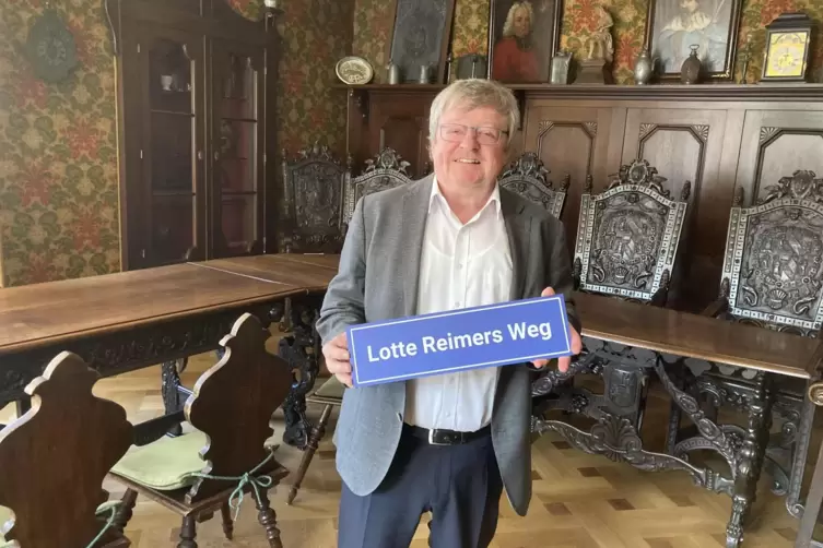 Manfred Dörr mit dem Straßenschild zu Ehren Lotte Reimers. 