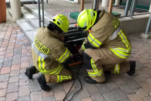 Feuerwehrleute beim Aufbau eines Notstromaggregats am Rathaus in Meckenheim. 