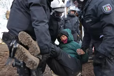 Polizisten tragen bei der Räumung von Lützerath eine Demonstrantin fort. 