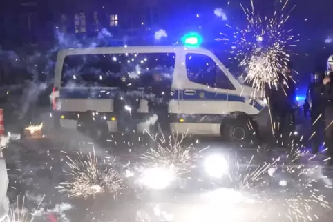 Polizeibeamte in Berlin stehen hinter explodierendem Feuerwerk in der Silvesternacht. Die Angriffe werfen Fragen auf, wie es so 