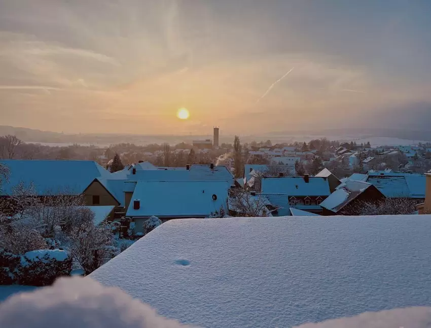Eine zauberhafte Kulisse bilden die schneebedeckten Dächer in Dreisen vor der aufgehenden Sonne.