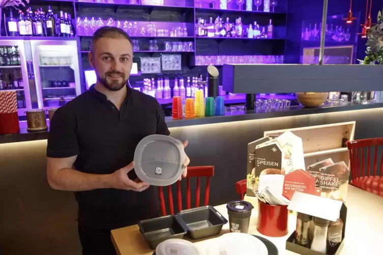 Ergert Azize, Betriebsleiter von „Sissi und Franz“, zeigt, was es in dem Burgerladen an Mehrweggeschirr gibt.